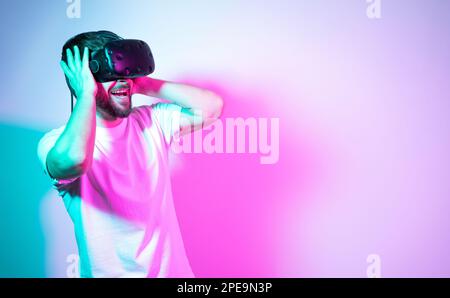 Excited man using VR glasses, experiencing ar virtual reality adventure with hands on his head screams emotionally with pleasure. Concept interactive Stock Photo