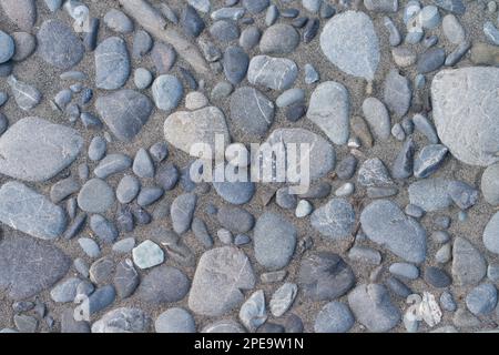 Rock texture background with smooth stones and sand on a beach area New Zealand. Stock Photo