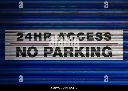 No parking sign at anytime and 24 hour access on blue painted metal garage door, Melbourne Australia. Stock Photo