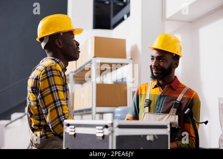 Two african american warehouse colleagues chatting at counter desk. Ecommerce store retail storehouse managers discussing customer order dispatching and standing near reception table Stock Photo