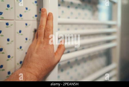 Man's hand checking temperature of heating radiator. Stock Photo