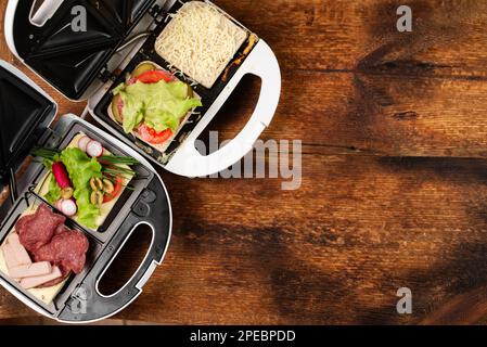 https://l450v.alamy.com/450v/2pebpdd/different-types-of-sandwiches-in-a-sandwich-maker-on-a-wooden-background-place-for-text-2pebpdd.jpg