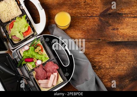 https://l450v.alamy.com/450v/2pebpde/different-types-of-sandwiches-in-a-sandwich-maker-on-a-wooden-background-place-for-text-2pebpde.jpg