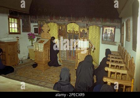 Sub Piatra Monastery, Alba County, Romania, 2001. Nuns and priest praying during the religious service in the 18th century wooden church. Stock Photo