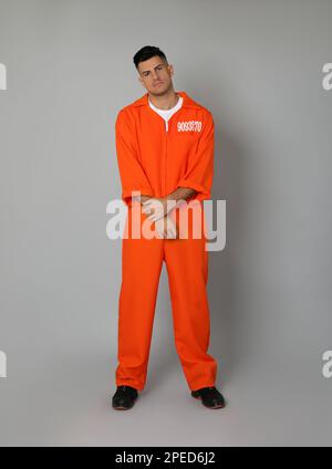 Prisoner in orange jumpsuit on grey background Stock Photo