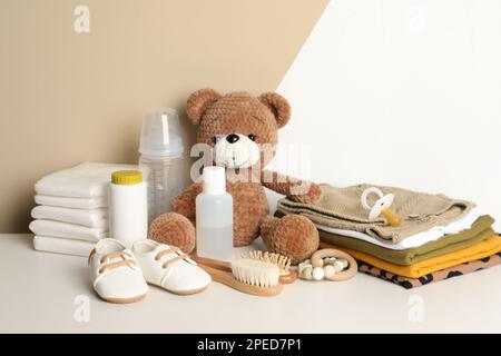 Baby clothes, toy bear and accessories on white table Stock Photo