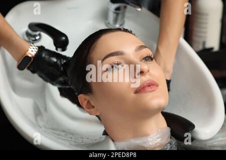 Hairdresser rinsing out dye from woman's hair in beauty salon Stock Photo