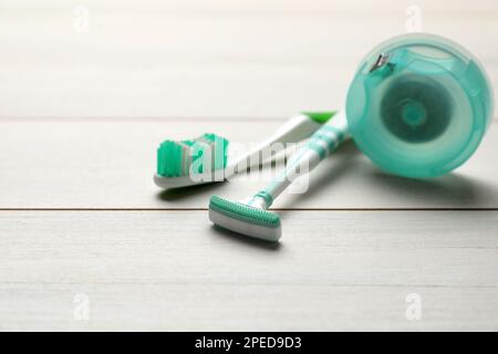 Tongue cleaner, toothbrush and dental floss on white wooden table, closeup Stock Photo