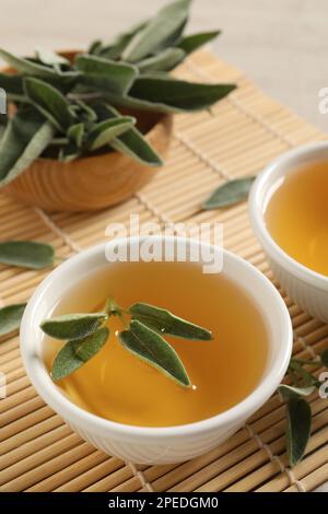 Cup of aromatic sage tea with fresh leaves on table Stock Photo
