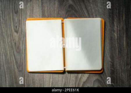 Notepad with blank pages on wooden table. High angle view of open notebook copy space for text. Taking notes concept. Blurry background. Stock Photo