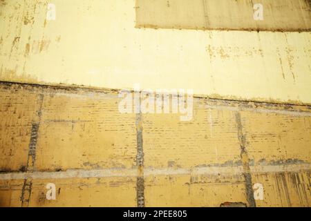 Brick wall of an old house painted yellow and ocher colors. Weathered stained wall textured background Stock Photo