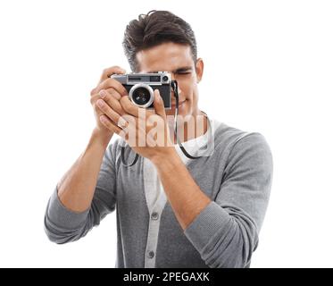 Having fun with his hobby. Portrait of a young man holding a camera and taking pictures against a white background. Stock Photo