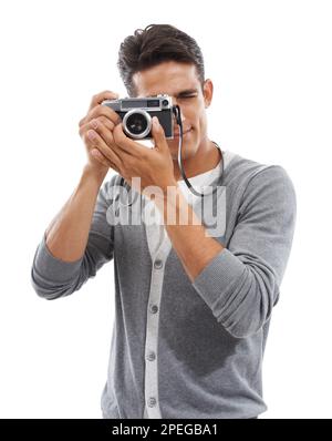 Capturing that special moment. Portrait of a young man holding a camera and taking pictures against a white background. Stock Photo