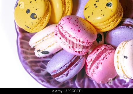 Sweet macaroons macarons in bowl top view. French cookies with vanilla, raspberry, lemon and strawberry. Pastry shop card Stock Photo