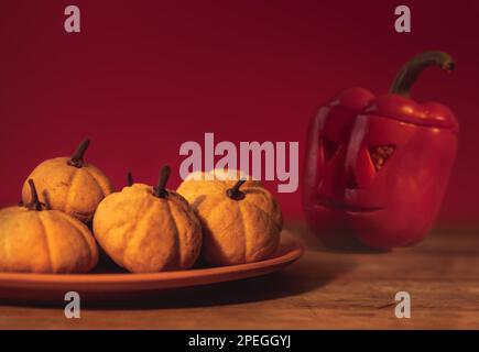 Halloween cookie with pumpkin and cinnamon on ceramic plate and baked pepper red background Stock Photo