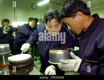 North Korean workers check the quality of stainless steel cooking