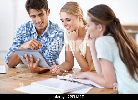 They make a great design team. Three young entrepreneurs working together on a digital tablet. Stock Photo