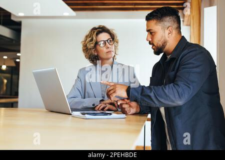 Colleagues discussing a business project in an office. Professional business people having a meeting. Collaboration and teamwork between two business Stock Photo
