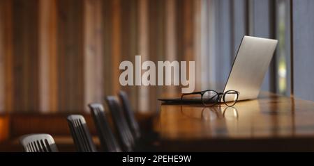 Modern and empty office desk with a laptop, computer, and eyeglasses. Still life shot of a professional working space in a coworking office. Stock Photo
