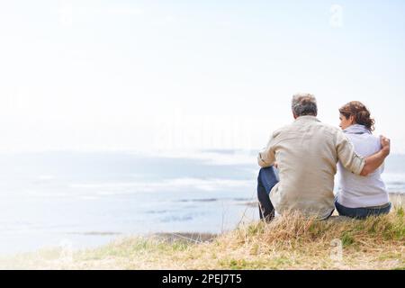 Taking in the scenery. Portrait of a mature couple sitting in the countryside. Stock Photo
