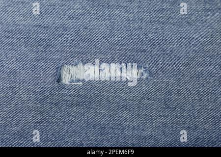 Torn, ripped jeans fabric background texture. Torn jeans fabric cloth textile material. Stock Photo