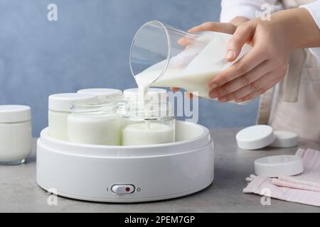 https://l450v.alamy.com/450v/2pem7gp/woman-pouring-milk-into-glass-jar-at-grey-table-closeup-making-yogurt-2pem7gp.jpg