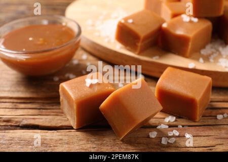 Yummy caramel candies and sea salt on wooden table, closeup Stock Photo