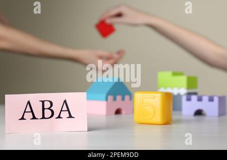 Paper card with abbreviation ABA (Applied behavior analysis) and blocks on white table, space for text Stock Photo