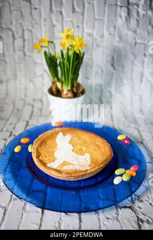 An Easter pie with colorful candy and wild daffodil flowers in a pot Stock Photo
