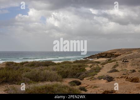 Light brown soil, full of stones and rocks on the west coast of the island at the coast of Atlantic ocean. Intense clouds in the winter. West coast (a Stock Photo