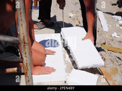 Man construction worker cutting polystyrene foam heat insulation with ...