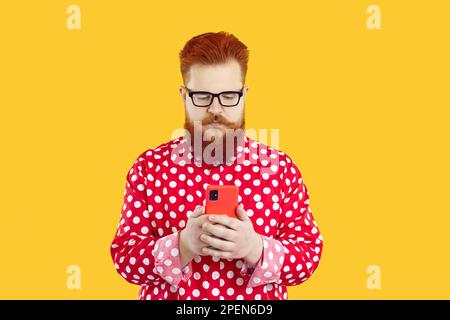 Serious funny bearded fat young guy making call or text messaging on mobile phone Stock Photo