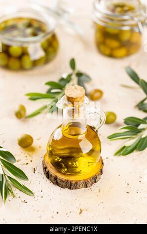 Bottle of fresh extra virgin olive oil and green olives with leaves Stock Photo