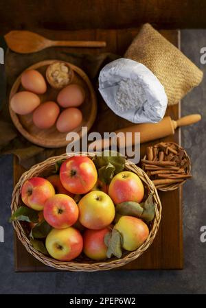 Top view on a ripe apples on a wooden table in basket with ingredients for pie near Stock Photo