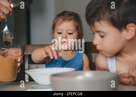 Mother and children baking in kitchen together while preparing pancake batter or muffin mix. Family cooking dessert, kid learning and cooking snack Stock Photo
