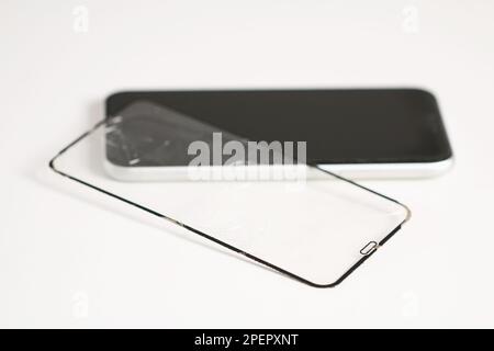 The man removes the old cracked protective glass from the phone. Broken protective glass Stock Photo