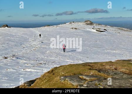 A hiker walking on the mountain covered by snow in Dartmoor National Park, UK Stock Photo