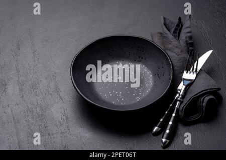 Empty plate with fork and knife on dark stone table. With copy space Stock Photo