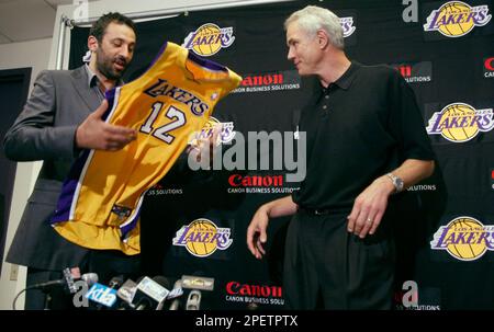 Gary Payton II, 10, foreground, examines his father's new Los Angeles Lakers'  jersey while Gary Payton, right, talks with Laker great James Worthy, left,  after a news conference, Thursday, July 17, 2003