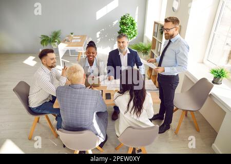Happy multicultural business people discussing corporate project at boardroom table Stock Photo