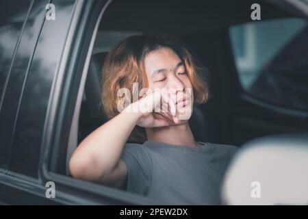 Young asian man with long hair sleeping in his car. Stock Photo