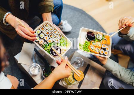 Three people enjoying sushi together while seated around a table Stock Photo