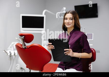 Doctor dentist working in office, using clipboard and making notes. Stock Photo