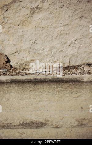 A full frame closeup of an old limestone wall that is heavily weathered and worn due to aging. Stock Photo