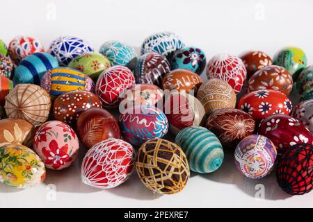 Many different colored Easter eggs lie side by side on a white background. Stock Photo