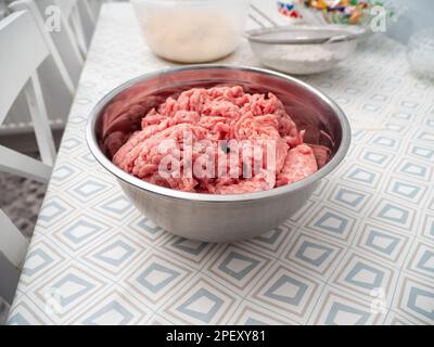 Minced meat in a metal bowl on the kitchen table. Close-up. Stock Photo