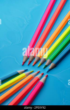 A set of vibrant colored pencils of different hues isolated on a blue background. Stock Photo