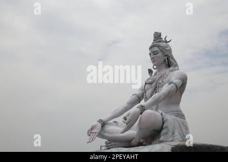 Statue of lord Shiva. Hindu idol near Ganges River water, Rishikesh, India. The first Hindu God Shiva. Sacred places for pilgrims in Rishikesh. Stock Photo