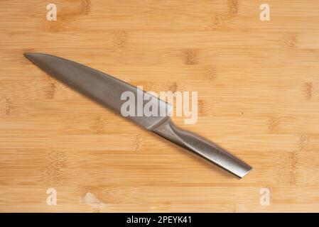 Kitchen knife made of steel on wooden table. Stock Photo