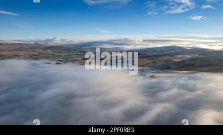 Cloud inversion above the Cumbrian village of Raven Stonedale on a cold winters day, looking towards Wild Boar Fell. Yorkshire Dales National Park, UK. Stock Photo